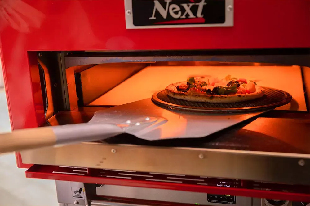 ピザ窯でピザを焼き上げる